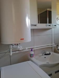 a white bathroom with a sink and a mirror at Vila Milica in Kladovo