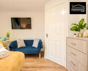 ein Schlafzimmer mit einem blauen Sofa und einem Schreibtisch in der Unterkunft Bright and Cosy Studio Apartment by Jesswood Properties Short Lets With Free Parking Near M1 & Luton Airport in Luton