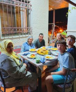 Petra downtown house في وادي موسى: مجموعة من الناس يجلسون حول طاولة يأكلون الطعام