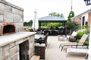 un patio con chimenea de piedra y cenador en As You Like It Bed and Breakfast, en Niagara on the Lake
