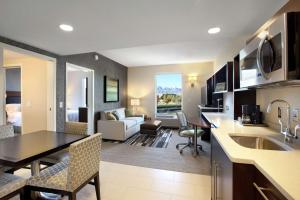 een keuken en een woonkamer met een tafel en stoelen bij Home2 Suites by Hilton West Valley City in West Valley City