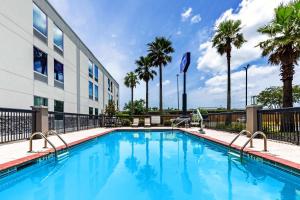 a swimming pool in front of a building with palm trees at Hampton Inn Sulphur in Sulphur