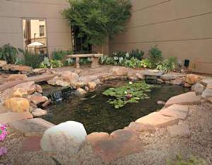 a garden with a pond with a table and flowers at Hampton Inn & Suites Stillwater in Stillwater