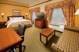 a hotel room with a bed and a couch and a television at Hampton Inn & Suites Stillwater in Stillwater