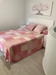 een slaapkamer met een bed met een roze en witte quilt bij Apartamento Rota Progreso 5 in Rota