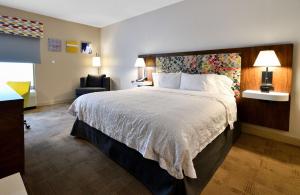 a hotel room with a large bed and a chair at Hampton Inn Santee-I-95 in Santee