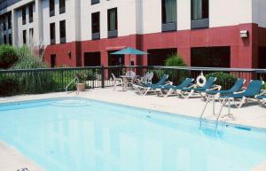 a swimming pool with chairs and a table and a building at Hampton Inn Sanford in Sanford