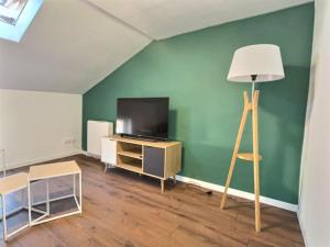 een woonkamer met een televisie en een vloerlamp bij Le Saint-Quentin in Longeville-lès-Metz