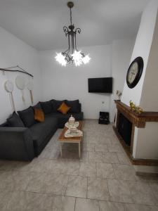 een woonkamer met een bank, een tafel en een klok bij La maison d Aspasia in Kamilari