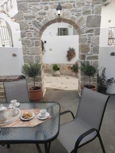 un patio con mesa, sillas y pared de piedra. en La maison d Aspasia en Kamilari