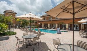 a patio with tables and umbrellas next to a pool at Homewood Suites by Hilton Sarasota in Sarasota