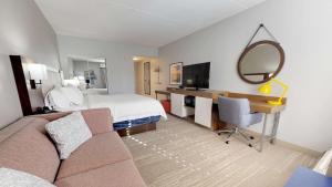 ein Hotelzimmer mit einem Bett und einem Schreibtisch mit einem Spiegel in der Unterkunft Hampton Inn St. Simons Island in Saint Simons Island