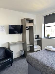 um quarto com uma cama, uma televisão e uma cadeira em Rooms Kingswood em Bristol