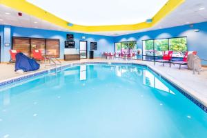 una piscina en un hotel con sillas y mesas rojas en Hampton Inn St Charles St Peters, en St. Charles