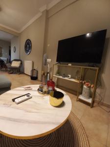 ein Wohnzimmer mit einem Tisch und einem großen Flachbild-TV in der Unterkunft Caldo Deluxe Apartment Thessaloniki in Thessaloniki