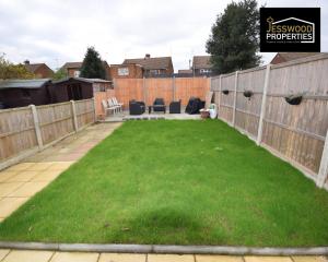 a backyard with a fence and a green lawn at Spacious 5 Bedroom, 3 Bath House by Jesswood Properties Short Lets For Contractors, With Free Parking Near M1 & Luton Airport in Luton