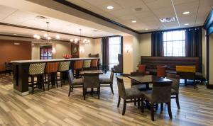 a restaurant with tables and chairs and a bar at Hampton Inn Orange City in Orange City