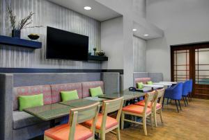a restaurant with tables and chairs and a flat screen tv at Hampton Inn & Suites by Hilton Syracuse Dewitt in East Syracuse