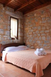 una camera da letto con un letto in un muro di pietra di Lalloudes Seaside Accommodation a Éxo Nímfion