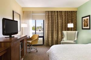 Habitación de hotel con cama y escritorio con TV. en Hampton Inn & Suites Tarpon Springs, en Tarpon Springs