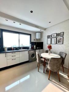 a kitchen with a table and chairs and a sink at Oasis Mehdia vue sur mer in Kenitra +1 photo