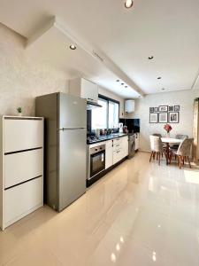a kitchen with a stainless steel refrigerator and a table at Oasis Mehdia vue sur mer in Kenitra