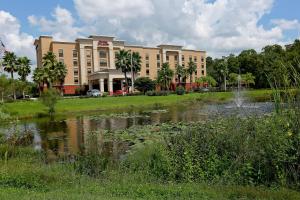 a large building with a pond in front of it at Hampton Inn & Suites Tampa-Wesley Chapel in Wesley Chapel