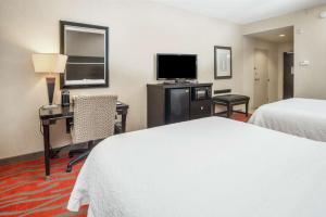 CatoosaにあるHampton Inn and Suites Tulsa/Catoosaのベッド2台、デスク、テレビが備わるホテルルームです。