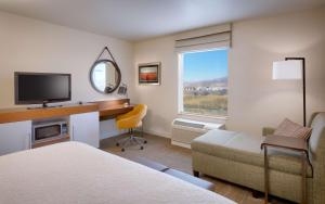 a hotel room with a bed and a desk with a television at Hampton Inn Tremonton in Tremonton
