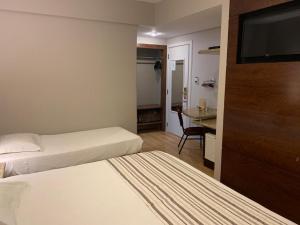 a hotel room with two beds and a flat screen tv at Bourbon Londrina Business Hotel in Londrina