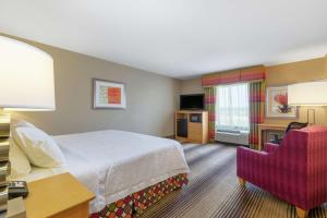a hotel room with a bed and a chair at Hampton Inn Texarkana in Texarkana