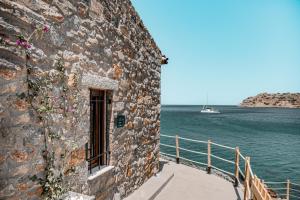 伊羅達的住宿－Petra Elounda Suites - Adults Only，水边的石头建筑,有船