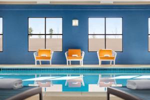 Hampton Inn & Suites Valparaiso في فالبارايسو: مسبح مع كرسيين وكراسي برتقال