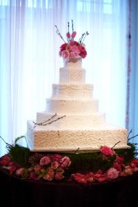 een witte bruidstaart met bloemen op een tafel bij Hilton Garden Inn Victorville in Victorville