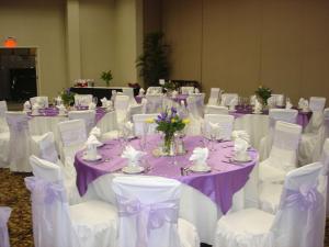 Hilton Garden Inn Victorville في فيكتورفيل: مجموعة طاولات مع كراسي بيضاء وملابس مائدة أرجوانية