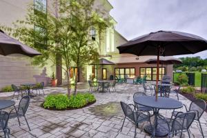 Hampton Inn and Suites New Hartford/Utica في New Hartford: فناء به طاولات وكراسي ومظلات