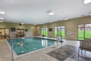 uma piscina numa sala com cadeiras e mesas em Hampton Inn and Suites New Hartford/Utica em New Hartford