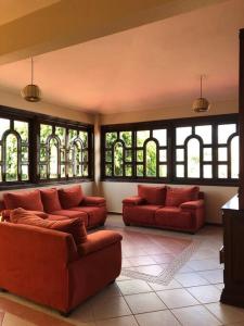 a living room with two red couches and windows at Casa Lídxi Beexha in Santa María Azompa