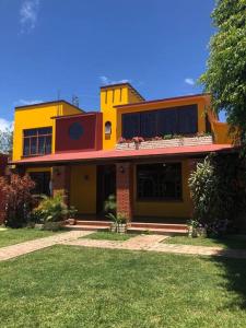a yellow and red building with a green yard at Casa Lídxi Beexha in Santa María Azompa