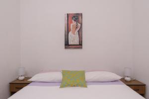 a bedroom with a bed and a painting on the wall at Apartmani Šuki in Trogir