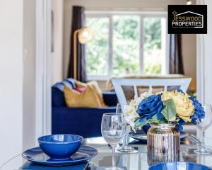 una mesa con placas azules y un jarrón con una flor en Spacious 3BR, 3BA House by Jesswood Properties Short Lets For Contractors, With Free Parking Near M1 & Luton Airport, en Luton