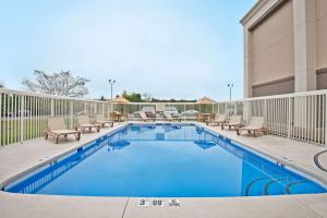 a swimming pool with chaise lounge chairs next to a building at Hampton Inn Winfield Teays Valley in Teays Valley Estates