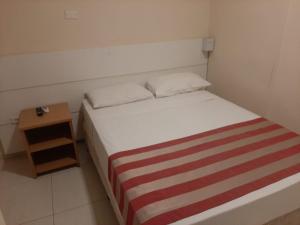 a small bedroom with a bed and a night stand at Atlantico Flat Gonzaga in Santos