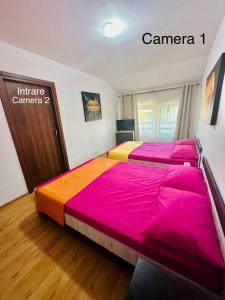a bedroom with a large bed with pink and orange sheets at Apartament Roxi Costinesti in Costinesti