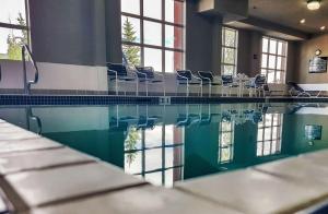 a swimming pool with chairs in a building at Hampton Inn & Suites by Hilton Edmonton International Airport in Leduc