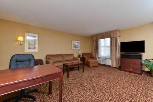 Hampton Inn & Suites by Hilton Edmonton International Airport في ليدوك: غرفة في الفندق مع مكتب وغرفة معيشة