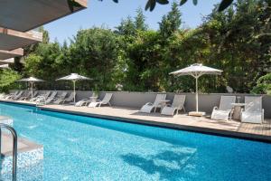 a swimming pool with lounge chairs and umbrellas next to a pool at DoubleTree by Hilton Kusadasi in Kuşadası