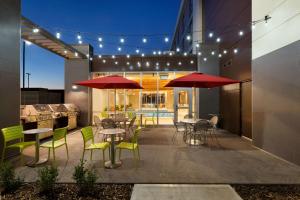 un patio con mesas, sillas y sombrillas en Home2 Suites by Hilton West Edmonton, en Edmonton