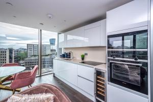 a kitchen with white cabinets and a table and chairs at Luxury 2 Bedroom Apartment in Tower Hill in London