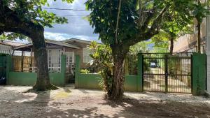 um portão em frente a uma casa com duas árvores em Villa do Aconchego em Ubatuba